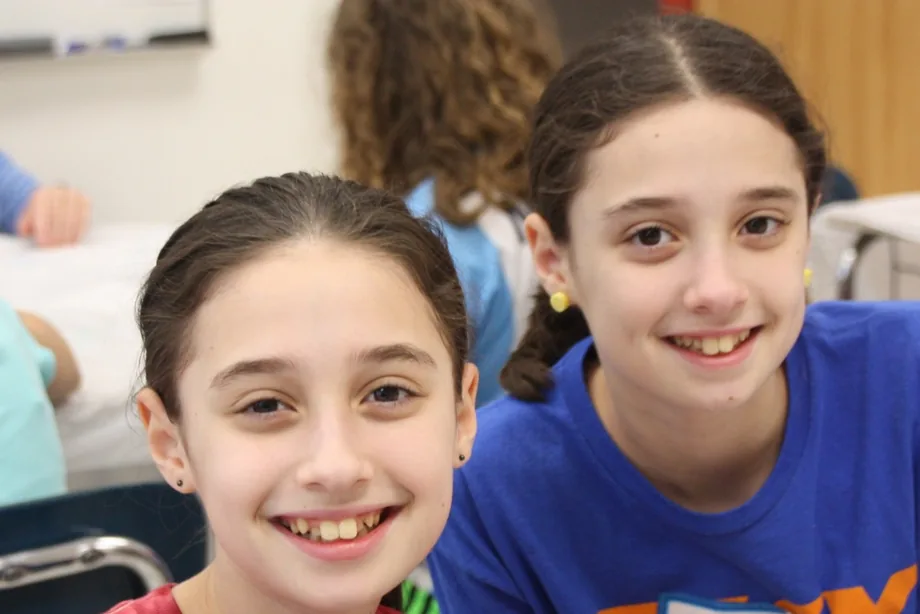 Two smiling campers sit side by side in a classroom
