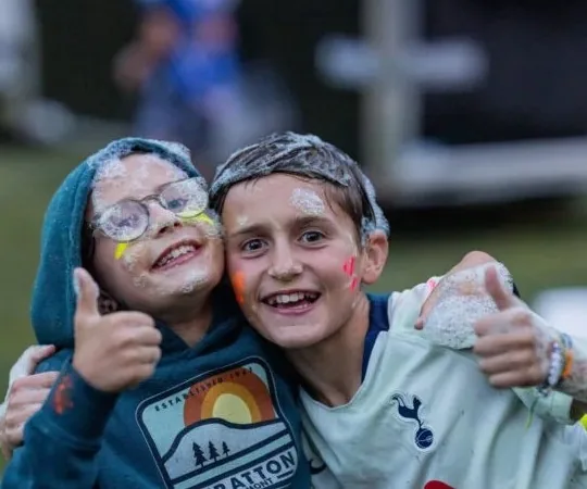 Two foam-covered friends grin and give a thumbs-up